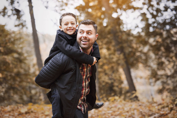father and son having fun in autumn park - Φωτογραφία, εικόνα