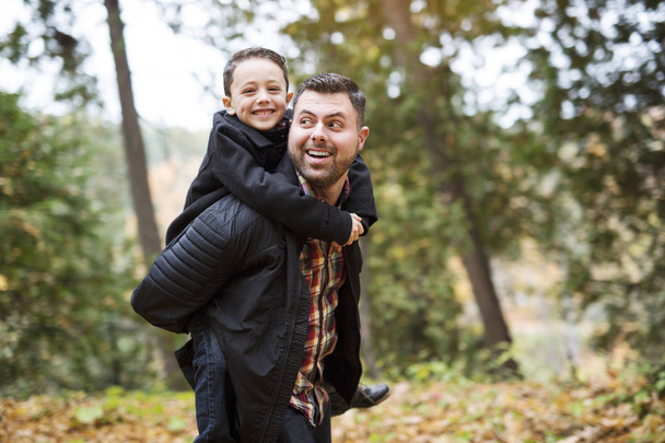 father and son having fun in autumn park - 写真・画像