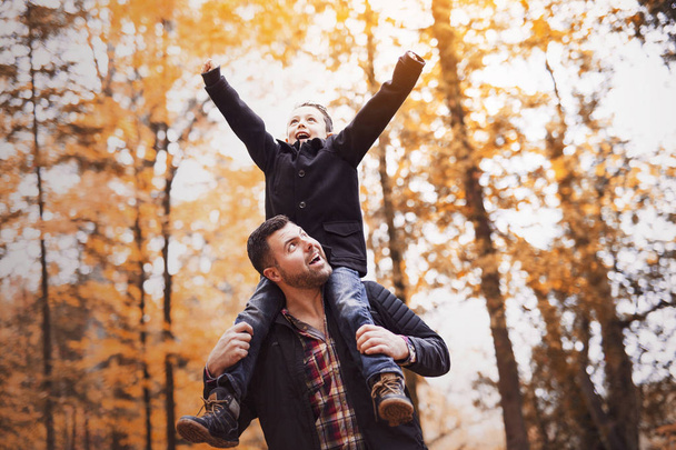 father and son having fun in autumn park - Фото, зображення