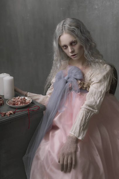 Темне Хеллоуїн портрет страшної поганої дівчини зомбі, що сидить у кріслі і збирає серця. Концептуальне фото
 - Фото, зображення