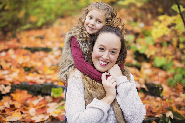 Young mother playing with her daughter in autumn park - Foto, Bild