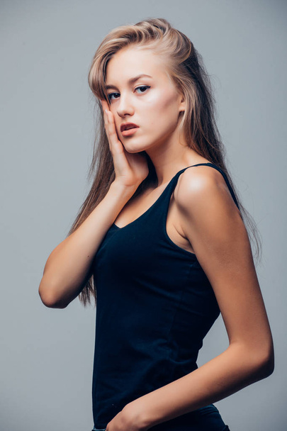 Beautiful young woman in black shirt on grey background - Фото, изображение
