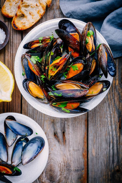 Delicious seafood mussels with with sauce and parsley.  Lemon and baguette . Clams in the shells.   - Φωτογραφία, εικόνα