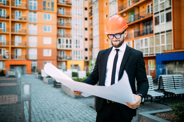 Engineer in front of modern building with plan looking at blueprint - Photo, Image