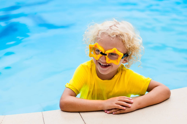 Child with goggles in swimming pool. Kids swim. - Photo, Image