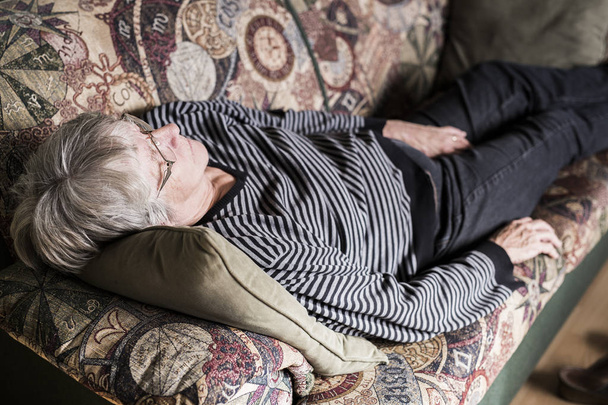 Senior woman relaxing on sofa - Fotó, kép