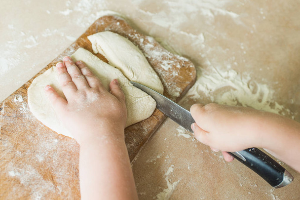Un enfant coupe la pâte crue
 - Photo, image
