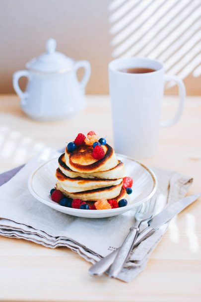 Frühstück, üppige Pfannkuchen mit frischen Beeren, Himbeeren und Blaubeeren und eine Tasse Tee - Foto, Bild