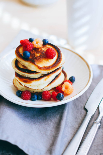 Breakfast, lush pancakes with fresh berries, raspberries and blueberries and a cup of tea - Foto, Imagem