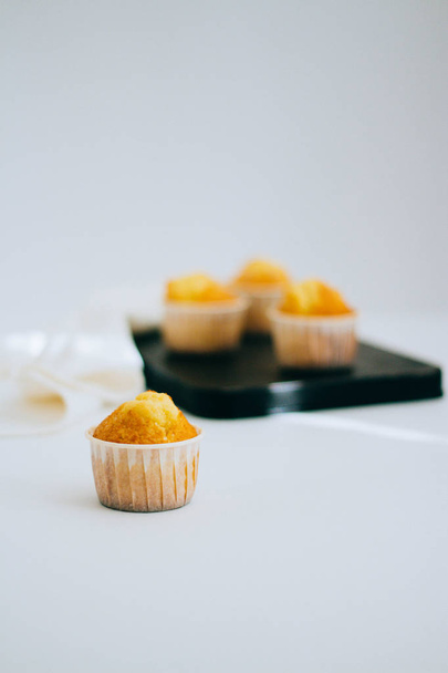 Muffins πορτοκαλιού σε ένα vintage μεταλλικό δίσκο, σε λευκό φόντο, μινιμαλισμό - Φωτογραφία, εικόνα