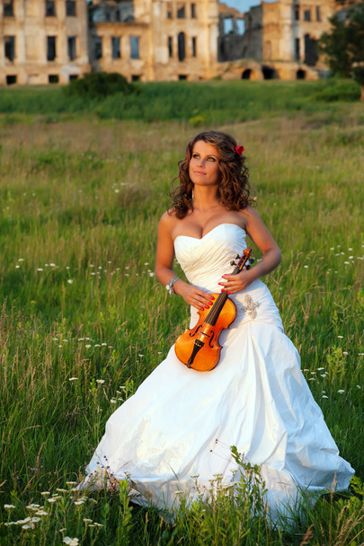 Smiling bride with violin in front of the ruins - Photo, image