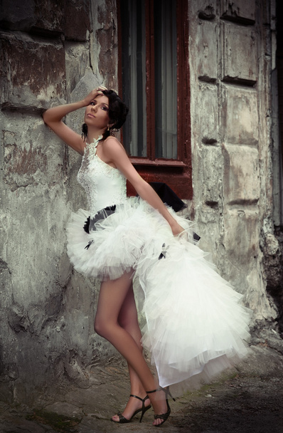 Beautiful bride leaning against the wall of an old building - Fotografie, Obrázek