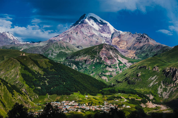 Monte Kazbek vista de Stepantsminda cidade na Geórgia em bom tempo
 - Foto, Imagem