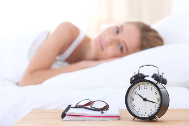 Young sleeping woman and alarm clock in bedroom at home. Young sleeping woman. - Φωτογραφία, εικόνα