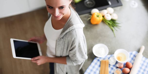 Woman baking at home following recipe on a tablet - 写真・画像