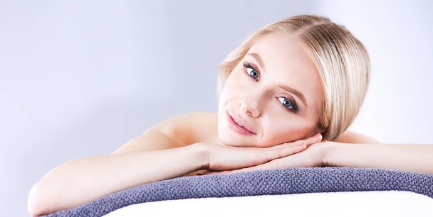 Young woman lying on a massage table,relaxing with eyes closed - Фото, изображение