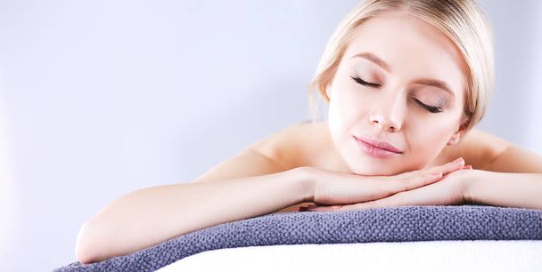Young woman lying on a massage table,relaxing with eyes closed - Foto, Imagen