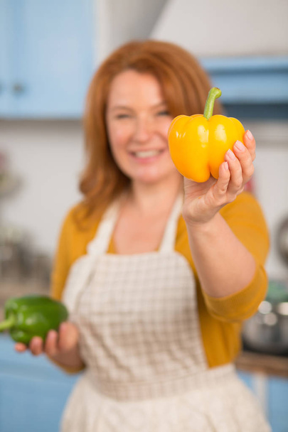 Close up view of yellow pepper in hand of attractive housewife. - Fotoğraf, Görsel