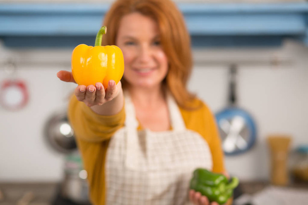Housewife holding bright yellow pepper in hand. - Photo, Image
