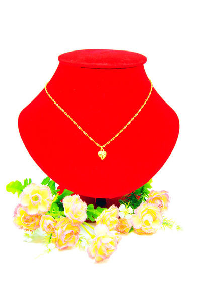 Collar de oro que pone en tela roja aislada en blanco
 - Foto, imagen