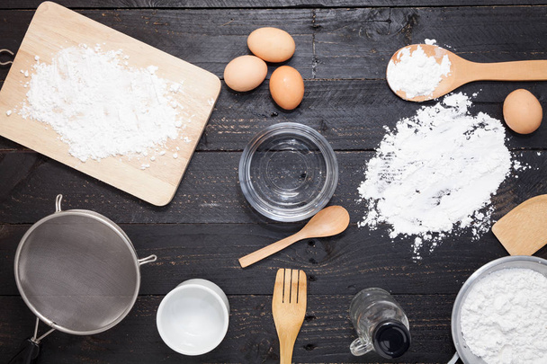 flour sprinkled with different kitchen tools on dark black backg - Φωτογραφία, εικόνα