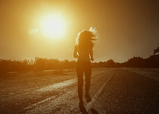 Oung, όμορφη, αθλητική γυναίκα με μακριά σγουρά μαλλιά το πρωί τρέχει - Φωτογραφία, εικόνα