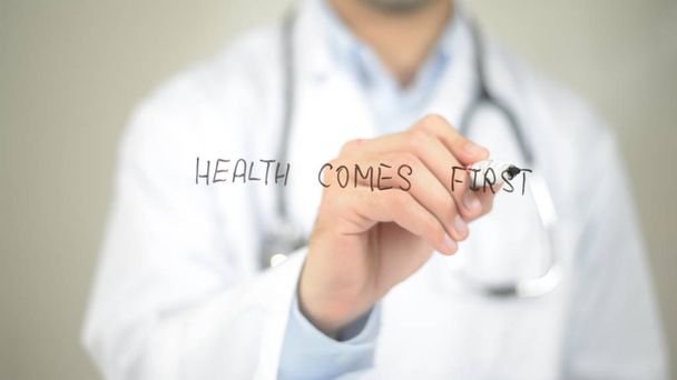 Health Comes First, Doctor writing on transparent screen - Photo, Image
