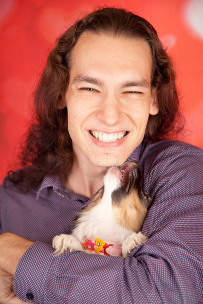 handsome smiling happy man with 3 months papillon little puppy. young boy and a dog are the best friends. - Photo, Image