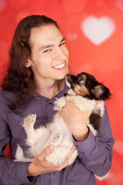 handsome smiling happy man with 3 months papillon little puppy. young boy and a dog are the best friends. - Photo, Image