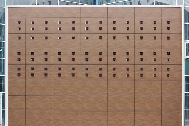 hnědé panely se sadou čtvercových otvorů na stěně nákupního komplexu při opravách - Fotografie, Obrázek