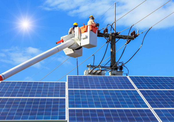 Elettricisti riparazione filo della linea elettrica sulla piattaforma di sollevamento idraulico benna con fotovoltaico nella centrale solare
  - Foto, immagini