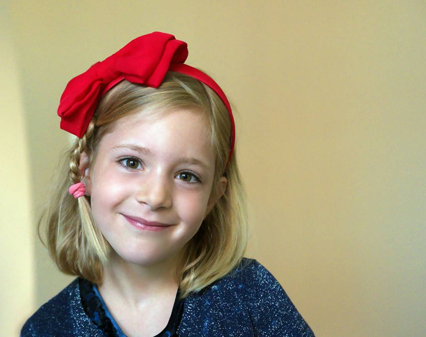 Pienen tytön muotokuva, jolla on punainen rusetti päässään
 - Valokuva, kuva