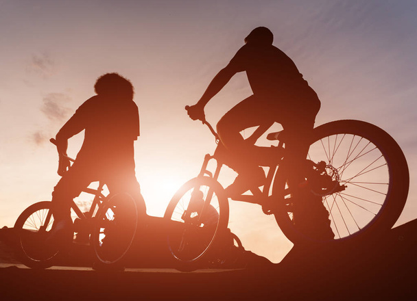 Cyclists on the ramp for jumping at sunset - Photo, Image