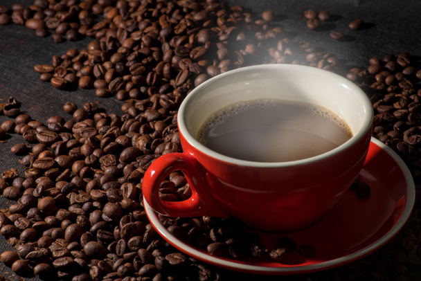 Hot coffee in red cup and coffee beans are the background. - Photo, Image