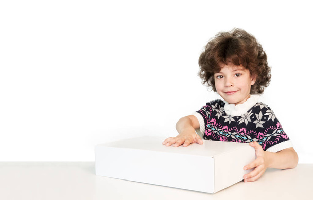 Surprised cute boy put his hand on the white box, smiling and looking at the camera. White background. - Foto, Bild