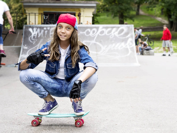 Nettes Mädchen mit Baseballmütze und Skateboard in einem Skatepark. Freizeit. - Foto, Bild
