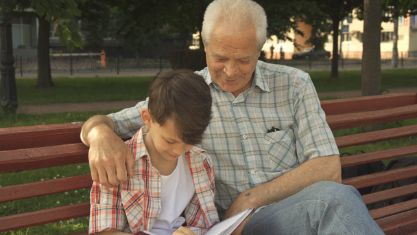 Niño pequeño escribe en su cuaderno lo que dice su abuelo
 - Imágenes, Vídeo
