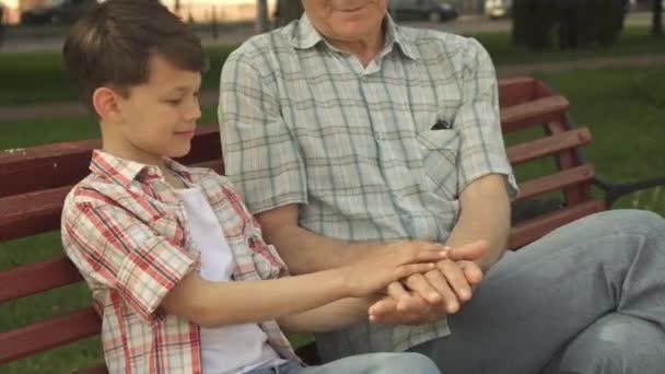 Starszy człowiek bawi się jego wnuk na ławce - Materiał filmowy, wideo