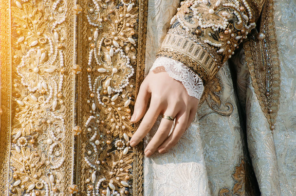 Roupas de uma mulher imperial histórica com tons pastel, uma mão com um anel com uma pedra preciosa
 - Foto, Imagem