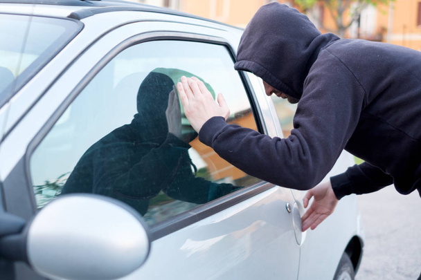 Κλέφτης που ψάχνει μέσα σε ένα παράθυρο αυτοκίνητο έτοιμο να κλέψει  - Φωτογραφία, εικόνα