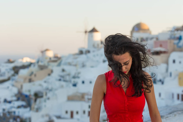 Santorini travel tourist brunette woman in red dress visiting famous white Oia village. - Фото, зображення