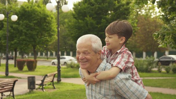 年配の男性は、彼の背中に彼の孫を保持しています。 - 映像、動画
