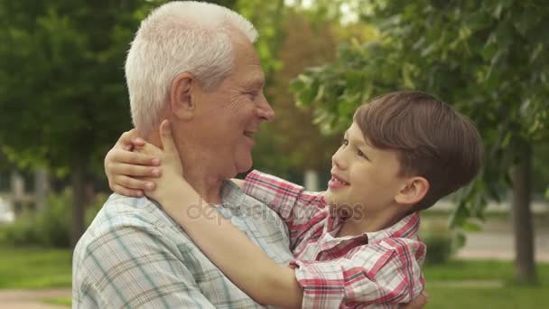 Little boy holds his hands behind his grandpas neck - Footage, Video