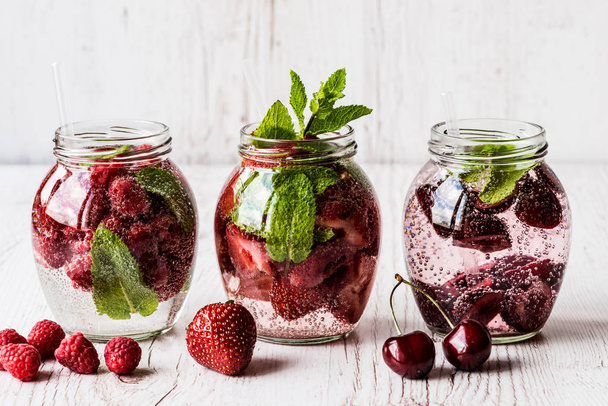 detox water with raspberry, strawberry, cherry on white wooden background. Healthy drinks - Φωτογραφία, εικόνα