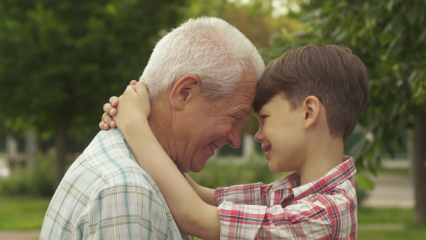 Senior und sein Enkel lehnen die Stirn aneinander - Filmmaterial, Video