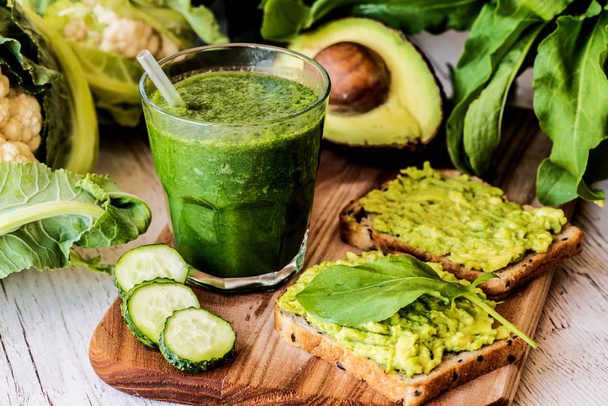 groene smoothie en twee broodjes met avocado. gezond veganistisch eten - Foto, afbeelding