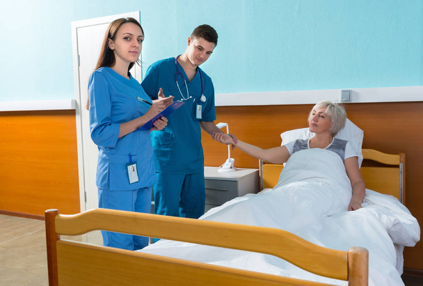 Médico e enfermeira atraentes do sexo masculino medindo o pulso e
  - Foto, Imagem
