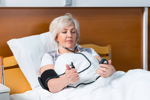 Female patient is measuring the arterial pressure using a medica - Photo, Image