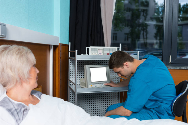 Young male doctor in uniform is looking at monitor of medical de - Фото, зображення
