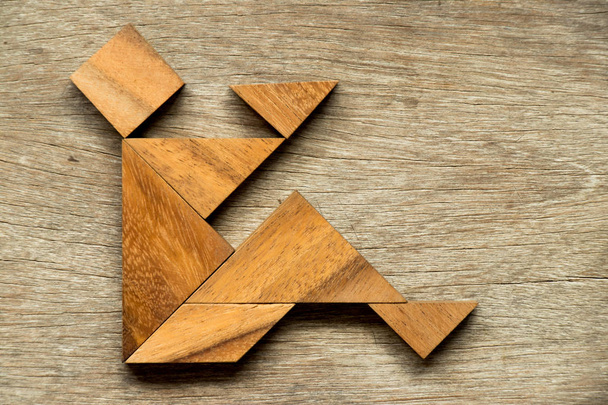 Wood tangram puzzle as man sit with read book or play mobile phone background - Фото, изображение
